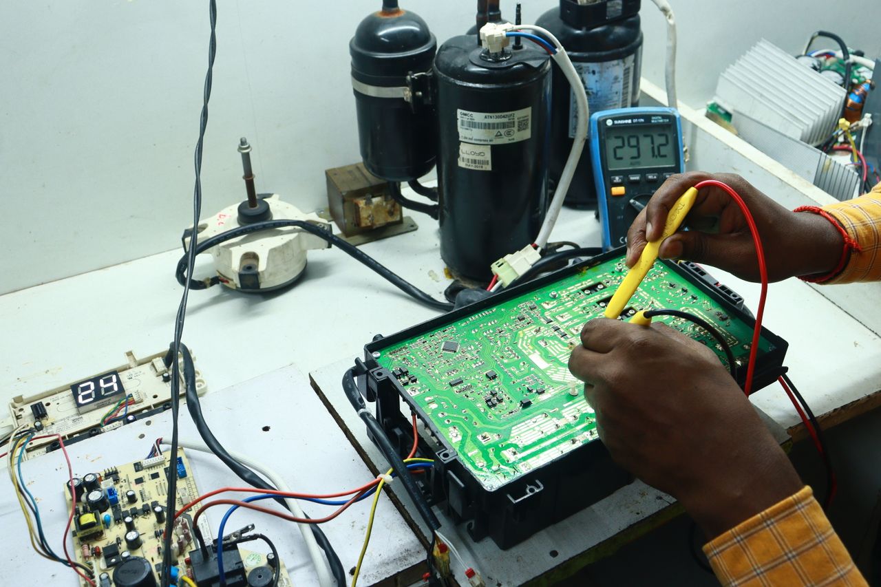 The Art of Drawing Readers In: Your attractive post title goes here Technician working on AC PCB with tools and equipment, captured in New Delhi workshop.